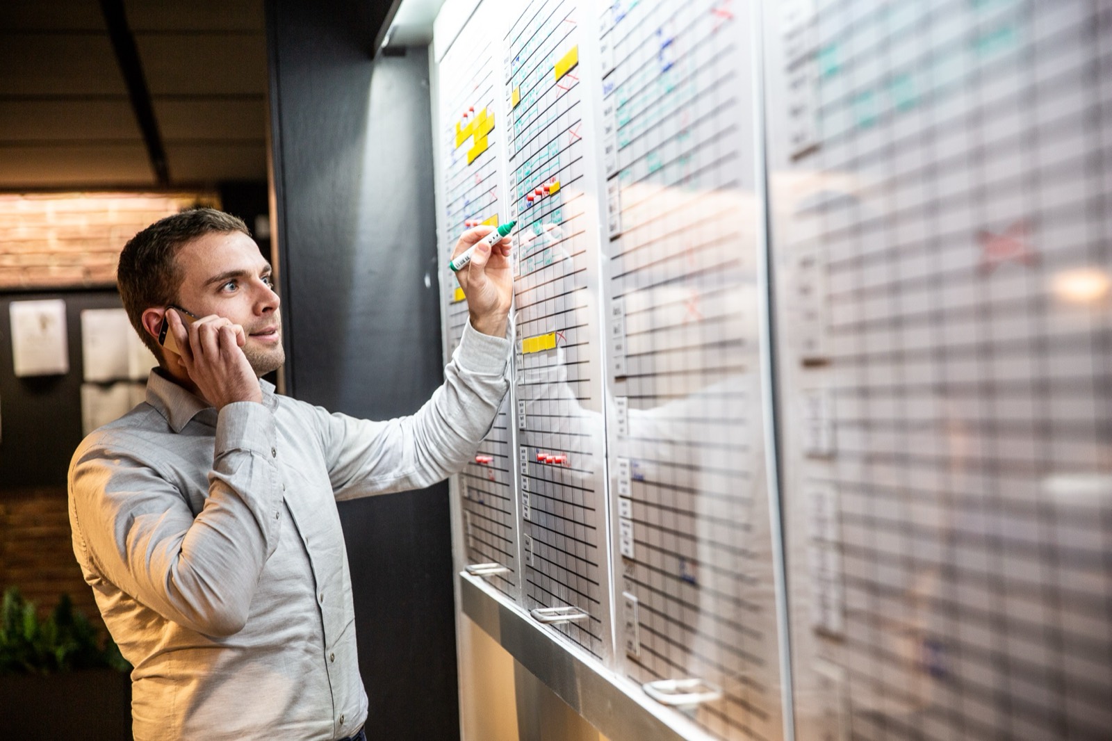 Medewerker overlegt telefonisch bij het planbord